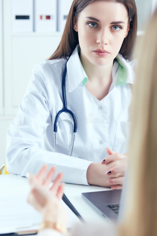 în cauză, o femeie doctor în medicina muncii, ascultând cu atenție plângerile pacienților în cadrul unui cabinet medical. asistenț royalty free stock photography