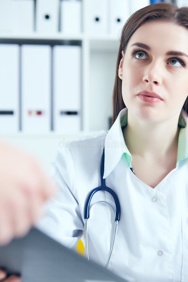 în cauză, o femeie doctor în medicina muncii, ascultând cu atenție plângerile pacienților în cadrul unui cabinet medical. asistenț royalty free stock image