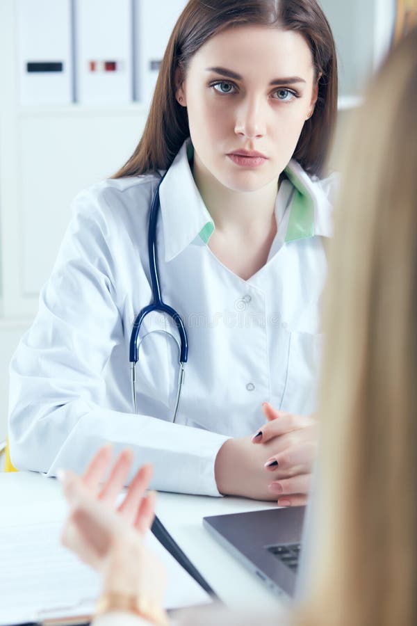 în cauză, o femeie doctor în medicina muncii, ascultând cu atenție plângerile pacienților în cadrul unui cabinet medical. asistenț royalty free stock photography