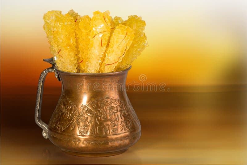 închiderea cristalului de dulciuri din piatră saffron într-un castron tradițional de cupru pe fond alb este adesea utilizat ca dis royalty free stock images