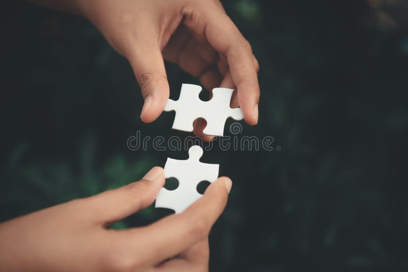 închiderea mâinilor femeii care leagă puzzle-ul de scena apusului stock image