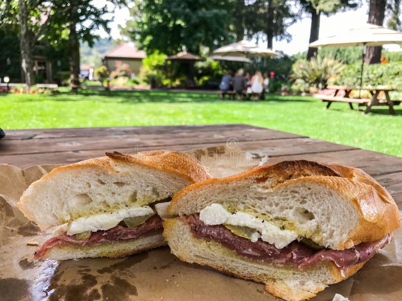 închiderea unei secțiuni transversale dintr-un sandviș cu brânză și roșii pe aluat pe o masă rustică din lemn cu picnic stock images