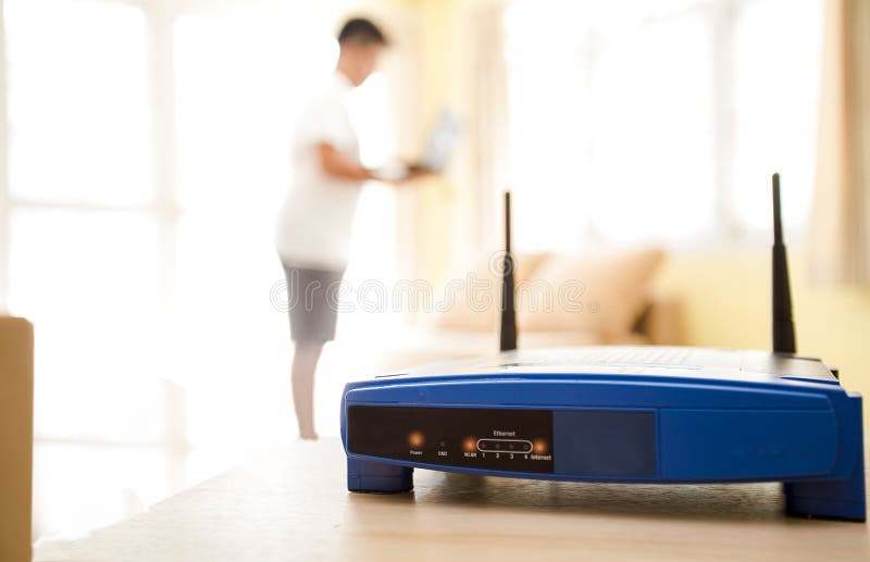 închiderea unui router wireless și a unui tânăr care utilizează laptopuri și laptopuri în sufragerie, în locuință, cu o fereastră royalty free stock photography