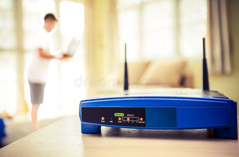 închiderea unui router wireless și a unui tânăr care utilizează laptopuri și laptopuri în sufragerie, în locuință, cu o fereastră stock images