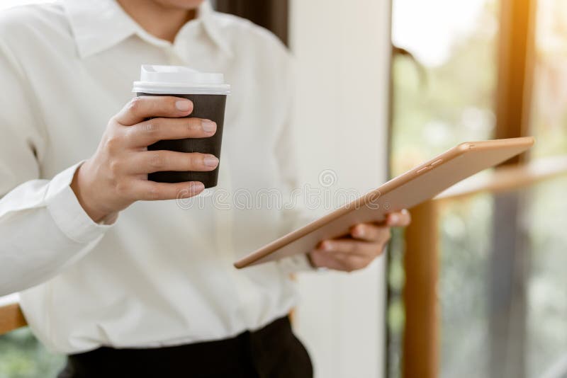 închideți tableta pentru business și țineți o ceașcă de cafea fierbinte stock photos