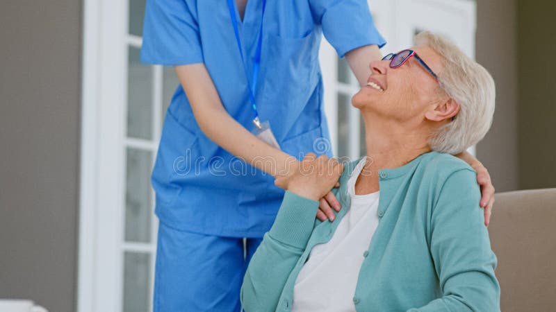 îngrijitorul îmbrățișează o femeie cu părul alb, singură, matură, într-o cameră spațioasă stock photography