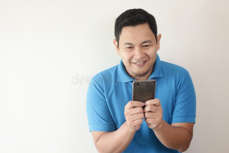 Ανάγνωση Texting νεαρών άνδρων που κουβεντιάζει στο τηλέφωνό του, χαμόγελο ευτυχές στοκ εικόνες Ανάγνωση Texting νεαρών άνδρων που κουβεντιάζει στο τηλέφωνό του, χαμόγελο ευτυχές στοκ εικόνες