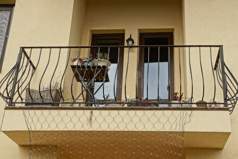 Ανοικτό μαύρο μπαλκόνι σιδήρου σε έναν καφετή τοίχο με τα παράθυρα στοκ φωτογραφία με δικαίωμα ελεύθερης χρήσης Ανοικτό μαύρο μπαλκόνι σιδήρου σε έναν καφετή τοίχο με τα παράθυρα στοκ φωτογραφία με δικαίωμα ελεύθερης χρήσης