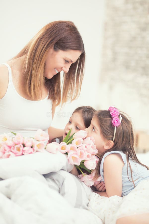 Ευτυχής έννοια ημέρας μητέρων ` s Mom με τα νέα δίδυμα κορών twocute στο κρεβάτι στην κρεβατοκάμαρα και μια ανθοδέσμη των τουλιπώ στοκ φωτογραφία Ευτυχής έννοια ημέρας μητέρων ` s Mom με τα νέα δίδυμα κορών twocute στο κρεβάτι στην κρεβατοκάμαρα και μια ανθοδέσμη των τουλιπώ στοκ φωτογραφία