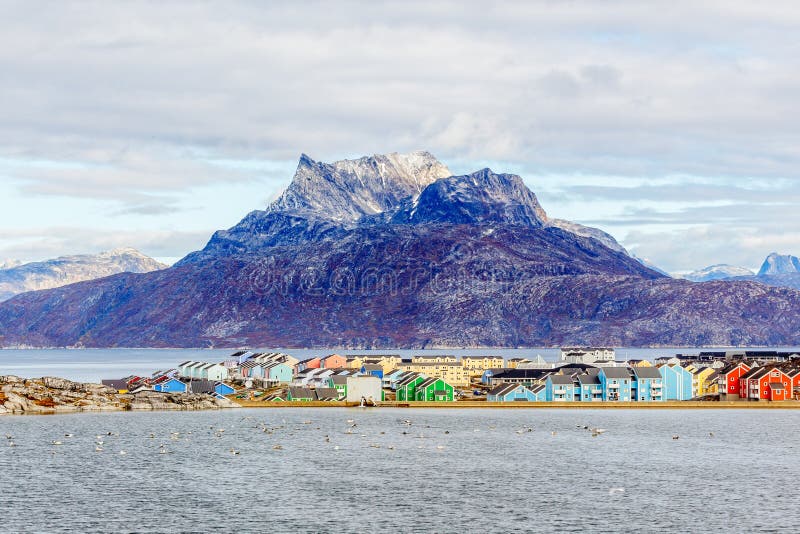 Ζωηρόχρωμα κτήρια Inuit στην κατοικημένη περιοχή της πόλης του Νουούκ με τη λίμνη στην αιχμή πρώτου πλάνου και χιονιού του βουνού στοκ φωτογραφία με δικαίωμα ελεύθερης χρήσης Ζωηρόχρωμα κτήρια Inuit στην κατοικημένη περιοχή της πόλης του Νουούκ με τη λίμνη στην αιχμή πρώτου πλάνου και χιονιού του βουνού στοκ φωτογραφία με δικαίωμα ελεύθερης χρήσης