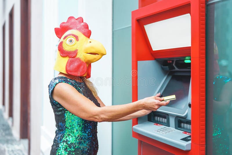 Η ώριμη γυναίκα που φορά τη μάσκα αποσύρει τα χρήματα από τη μηχανή μετρητών τραπεζών με τη χρεωστική κάρτα - υπερφυσική εικόνα κ στοκ εικόνες Η ώριμη γυναίκα που φορά τη μάσκα αποσύρει τα χρήματα από τη μηχανή μετρητών τραπεζών με τη χρεωστική κάρτα - υπερφυσική εικόνα κ στοκ εικόνες