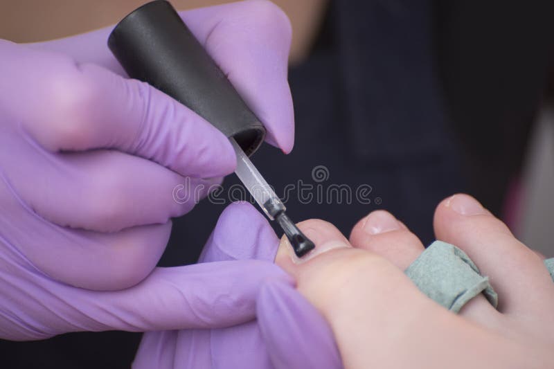 Κάλυψη toenails με την άχρωμη στιλβωτική ουσία καρφιών Κινηματογράφηση σε πρώτο πλάνο Σαλόνι μανικιούρ στοκ εικόνες Κάλυψη toenails με την άχρωμη στιλβωτική ουσία καρφιών Κινηματογράφηση σε πρώτο πλάνο Σαλόνι μανικιούρ στοκ εικόνες