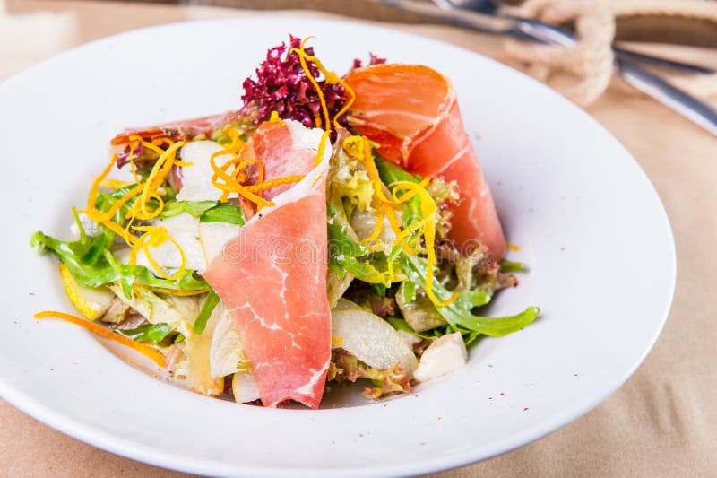 Κλείστε επάνω την πράσινη σαλάτα με το prosciutto και τα αχλάδια άσπρο στενό σε επάνω πιάτων εξυπηρετούμενος εστια& Εκλεκτική εστ στοκ εικόνες Κλείστε επάνω την πράσινη σαλάτα με το prosciutto και τα αχλάδια άσπρο στενό σε επάνω πιάτων εξυπηρετούμενος εστια& Εκλεκτική εστ στοκ εικόνες