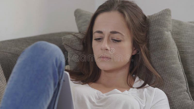 Νέα γυναίκα στις κυματωγές καναπέδων το Διαδίκτυο με έναν υπολογιστή ταμπλετών στοκ φωτογραφία με δικαίωμα ελεύθερης χρήσης Νέα γυναίκα στις κυματωγές καναπέδων το Διαδίκτυο με έναν υπολογιστή ταμπλετών στοκ φωτογραφία με δικαίωμα ελεύθερης χρήσης