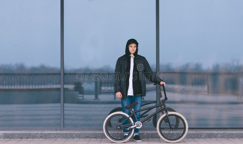Ο νεαρός άνδρας με ένα ποδήλατο BMX στέκεται στο υπόβαθρο ενός σκοτεινού τοίχου Πορτρέτο του αναβάτη BMX Πολιτισμός οδών στοκ φωτογραφία Ο νεαρός άνδρας με ένα ποδήλατο BMX στέκεται στο υπόβαθρο ενός σκοτεινού τοίχου Πορτρέτο του αναβάτη BMX Πολιτισμός οδών στοκ φωτογραφία