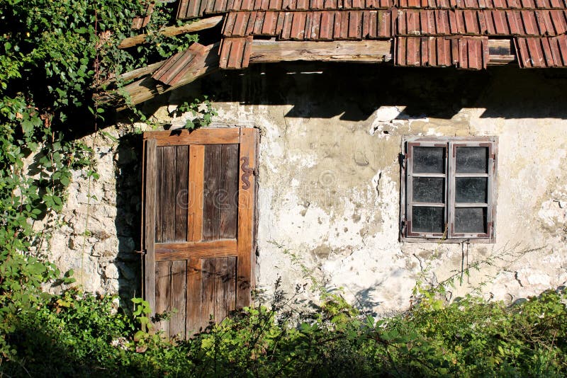 Οι ξύλινα πόρτες και τα παράθυρα που τοποθετούνται με το διακοσμητικό οξυδωμένο μέταλλο αρθρώνουν στον τοίχο του μικρού εγκαταλει στοκ φωτογραφίες Οι ξύλινα πόρτες και τα παράθυρα που τοποθετούνται με το διακοσμητικό οξυδωμένο μέταλλο αρθρώνουν στον τοίχο του μικρού εγκαταλει στοκ φωτογραφίες