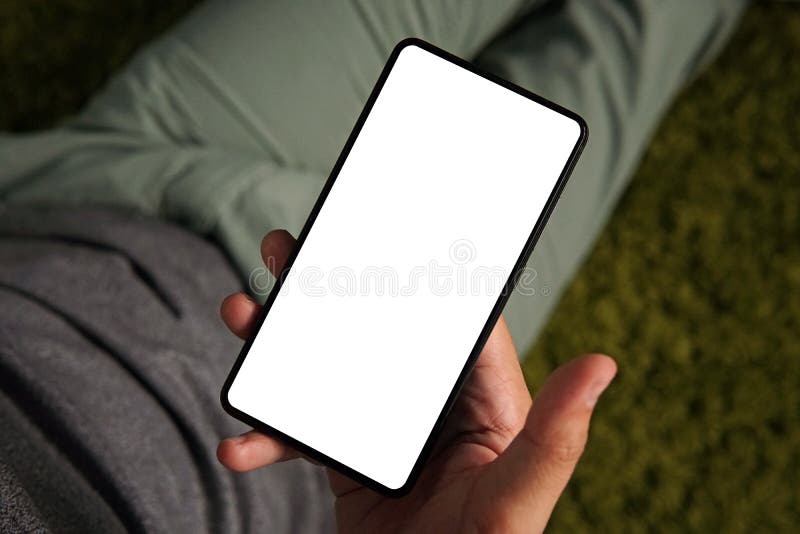 Ένα από επάνω προς τα κάτω handshot ενός νεαρού άνδρα που εξετάζει την άσπρη οθόνη ενός smartphone Το άτομο κρατά το smartphone σ στοκ φωτογραφία Ένα από επάνω προς τα κάτω handshot ενός νεαρού άνδρα που εξετάζει την άσπρη οθόνη ενός smartphone Το άτομο κρατά το smartphone σ στοκ φωτογραφία