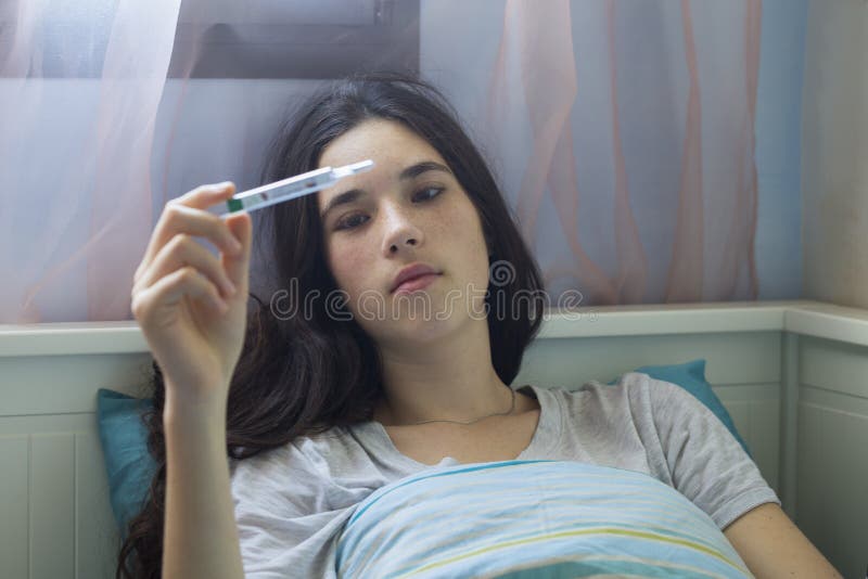Έφηβη στο πιασμένο κρύο κρεβατιών στο σπίτι, που αισθάνεται κακό στοκ εικόνα