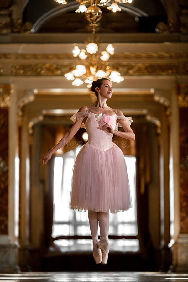 Όμορφο ballerina που χορεύει και που πηδά σε μια πολυτελή αίθουσα σε ένα ρόδινο φόρεμα στοκ εικόνες Όμορφο ballerina που χορεύει και που πηδά σε μια πολυτελή αίθουσα σε ένα ρόδινο φόρεμα στοκ εικόνες