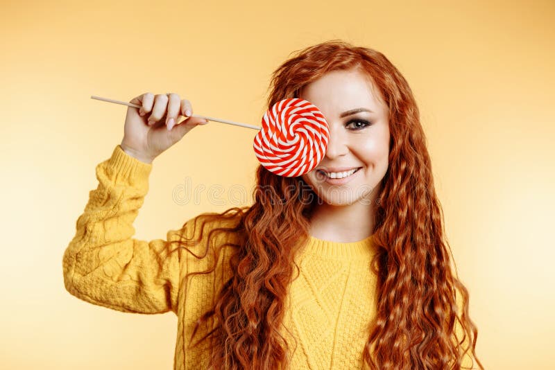 Όμορφο redhead womanl που κρατά ένα κόκκινα άσπρα lollipop και ένα χαμόγελο στοκ φωτογραφία με δικαίωμα ελεύθερης χρήσης Όμορφο redhead womanl που κρατά ένα κόκκινα άσπρα lollipop και ένα χαμόγελο στοκ φωτογραφία με δικαίωμα ελεύθερης χρήσης