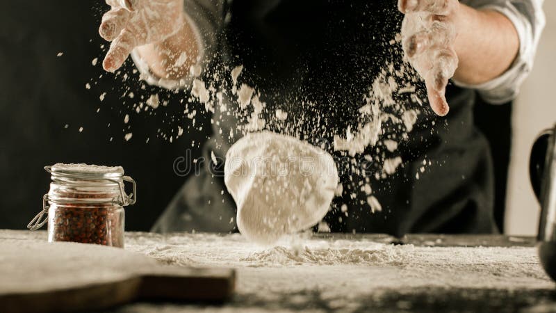 Τα αρσενικά χέρια αρχιμαγείρων ζυμώνουν τη ζύμη με το αλεύρι στον πίνακα κουζινών στοκ φωτογραφίες με δικαίωμα ελεύθερης χρήσης Τα αρσενικά χέρια αρχιμαγείρων ζυμώνουν τη ζύμη με το αλεύρι στον πίνακα κουζινών στοκ φωτογραφίες με δικαίωμα ελεύθερης χρήσης