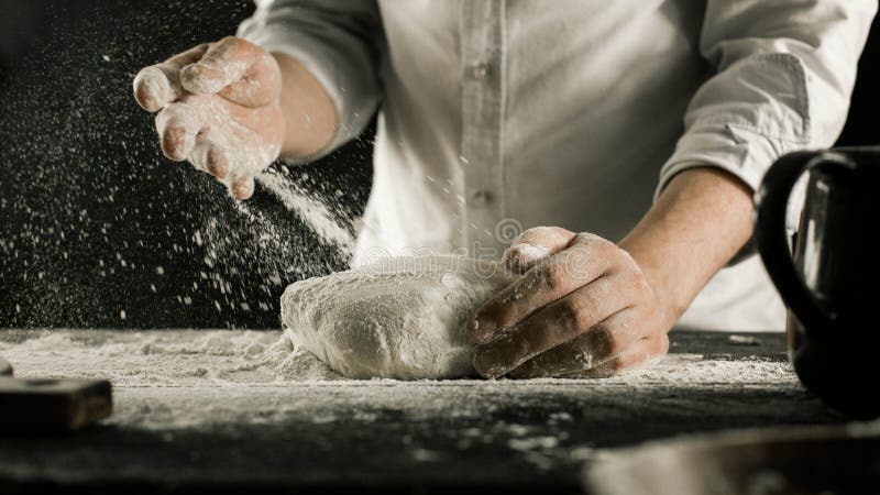 Τα αρσενικά χέρια αρχιμαγείρων ζυμώνουν τη ζύμη με το αλεύρι στον πίνακα κουζινών στοκ εικόνες Τα αρσενικά χέρια αρχιμαγείρων ζυμώνουν τη ζύμη με το αλεύρι στον πίνακα κουζινών στοκ εικόνες