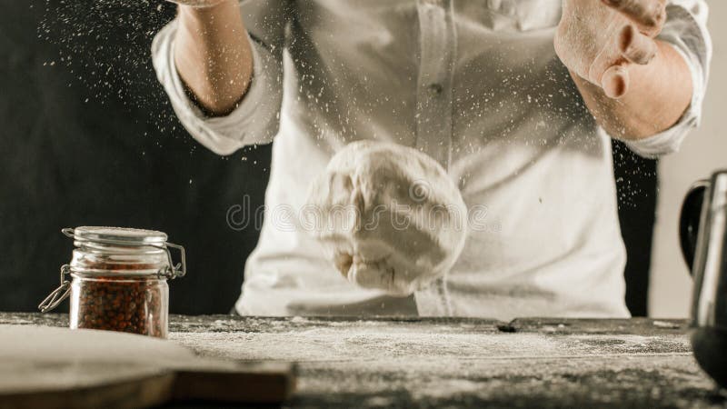 Τα αρσενικά χέρια αρχιμαγείρων ζυμώνουν τη ζύμη με το αλεύρι στον πίνακα κουζινών στοκ φωτογραφία με δικαίωμα ελεύθερης χρήσης Τα αρσενικά χέρια αρχιμαγείρων ζυμώνουν τη ζύμη με το αλεύρι στον πίνακα κουζινών στοκ φωτογραφία με δικαίωμα ελεύθερης χρήσης