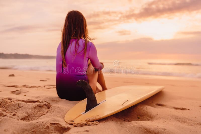 Τοποθέτηση γυναικών Surfer με την ιστιοσανίδα στην παραλία στο ηλιοβασίλεμα στοκ φωτογραφίες