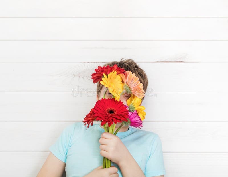 Χαριτωμένο αγόρι με τα λουλούδια gerbera ανθοδεσμών στοκ φωτογραφία με δικαίωμα ελεύθερης χρήσης Χαριτωμένο αγόρι με τα λουλούδια gerbera ανθοδεσμών στοκ φωτογραφία με δικαίωμα ελεύθερης χρήσης
