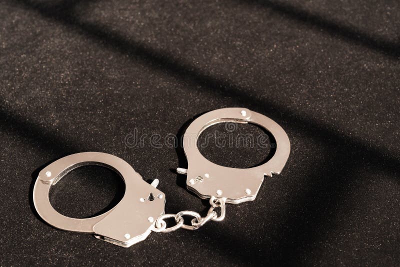 Χειροπέδες κάτω από τη σκιά ενός εμποδίου μετάλλων στοκ εικόνα με δικαίωμα ελεύθερης χρήσης Χειροπέδες κάτω από τη σκιά ενός εμποδίου μετάλλων στοκ εικόνα με δικαίωμα ελεύθερης χρήσης