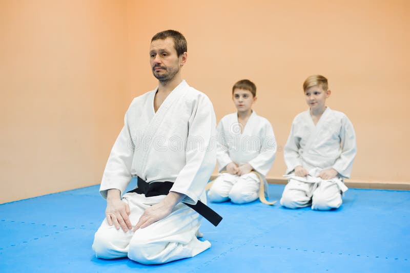 Дети в кимоно сидят на tatami с тренером на семинаре на боевых искусствах стоковые изображения rf Дети в кимоно сидят на tatami с тренером на семинаре на боевых искусствах стоковые изображения rf