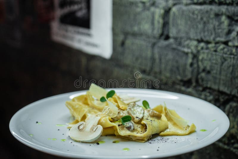 Аппетитная горячая закуска лапши со сметанообразным соусом champignon на предпосылке серой кирпичной стены в баре обед гинеи пред стоковые изображения rf Аппетитная горячая закуска лапши со сметанообразным соусом champignon на предпосылке серой кирпичной стены в баре обед гинеи пред стоковые изображения rf
