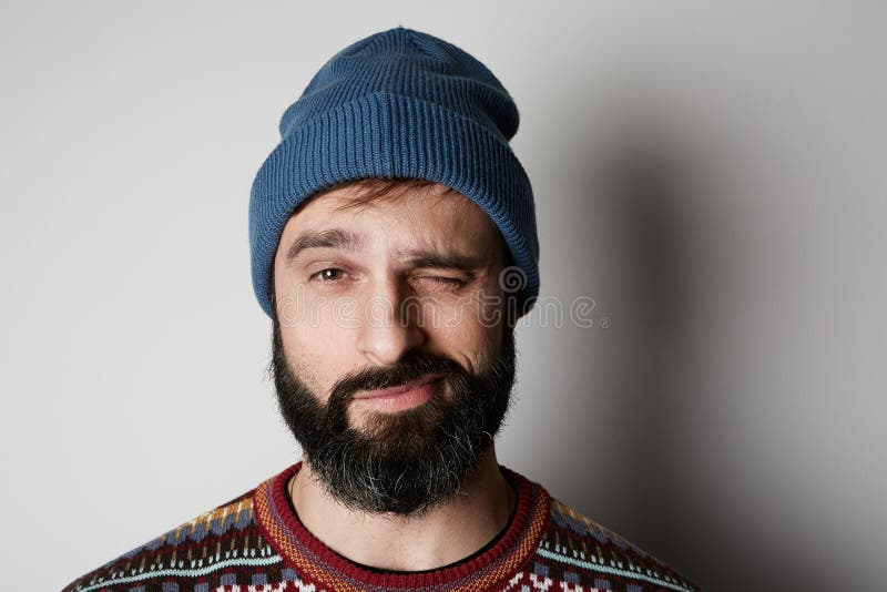 Бородатый хипстер нося голубой beanie и покрашенный свитер на белой предпосылке стоковая фотография rf Бородатый хипстер нося голубой beanie и покрашенный свитер на белой предпосылке стоковая фотография rf