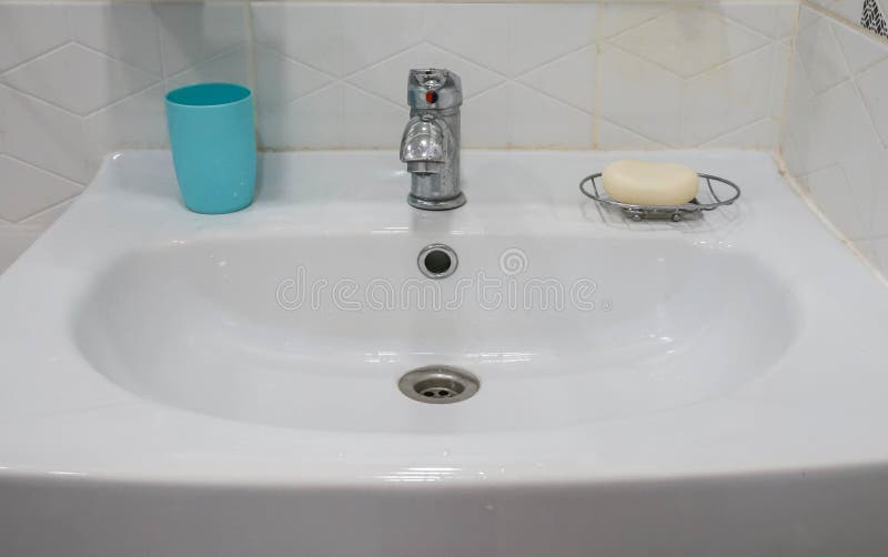 Белая керамическая раковина в bathroom с пластиковым стеклом для щетки и мылом для чистки руки стоковое изображение rf Белая керамическая раковина в bathroom с пластиковым стеклом для щетки и мылом для чистки руки стоковое изображение rf