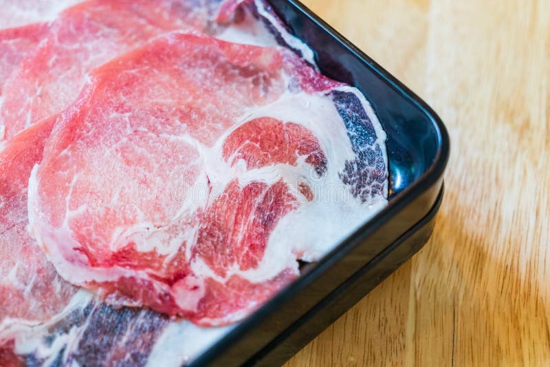 Взгляд сверху свежих тонких кусков свинины для Shabu, Sukiyaki, горячего бака или гриля на лотке барбекю латунном стоковое фото Взгляд сверху свежих тонких кусков свинины для Shabu, Sukiyaki, горячего бака или гриля на лотке барбекю латунном стоковое фото