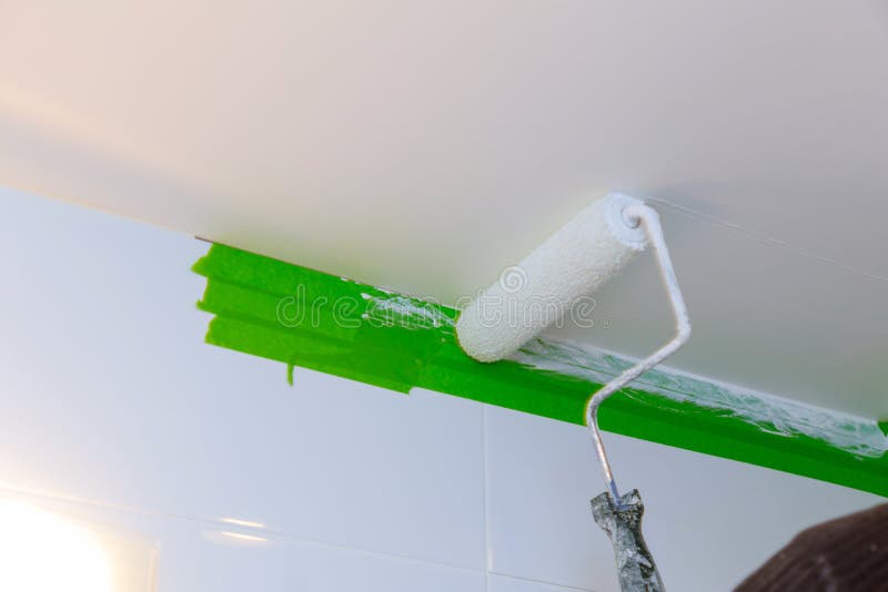 Вид сзади человека художника крася потолок в bathroom, с роликом краски стоковое фото rf Вид сзади человека художника крася потолок в bathroom, с роликом краски стоковое фото rf