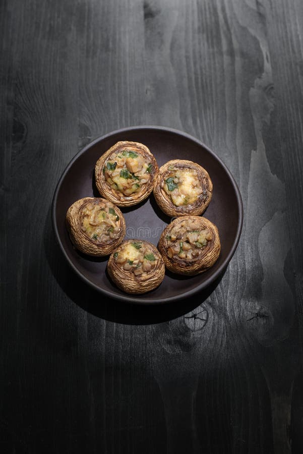 Закуска Champignon: испеченный сыр в шляпах Домодельная еда, грибы круга цветка на черной плите на деревянном столе стоковые фото Закуска Champignon: испеченный сыр в шляпах Домодельная еда, грибы круга цветка на черной плите на деревянном столе стоковые фото