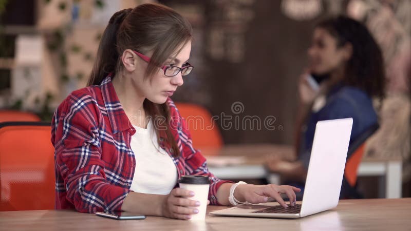 Интеллектуальная женщина печатая на ноутбуке в кафе, фрилансер работая на новом проекте стоковые фотографии rf Интеллектуальная женщина печатая на ноутбуке в кафе, фрилансер работая на новом проекте стоковые фотографии rf