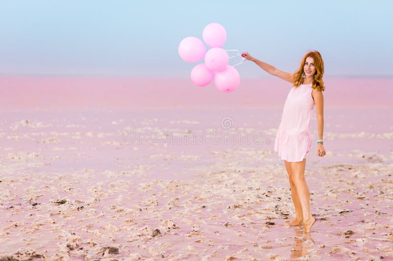 Красивая женщина с baloons на розовом озере соли стоковое изображение rf Красивая женщина с baloons на розовом озере соли стоковое изображение rf