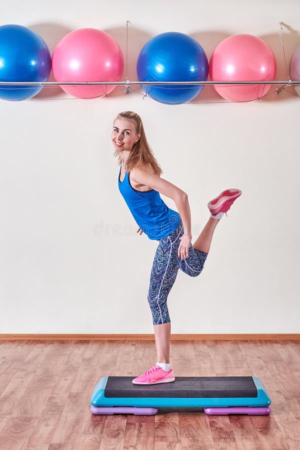 Молодая sportive женщина работая в спортзале используя платформу шага стоковое фото rf Молодая sportive женщина работая в спортзале используя платформу шага стоковое фото rf
