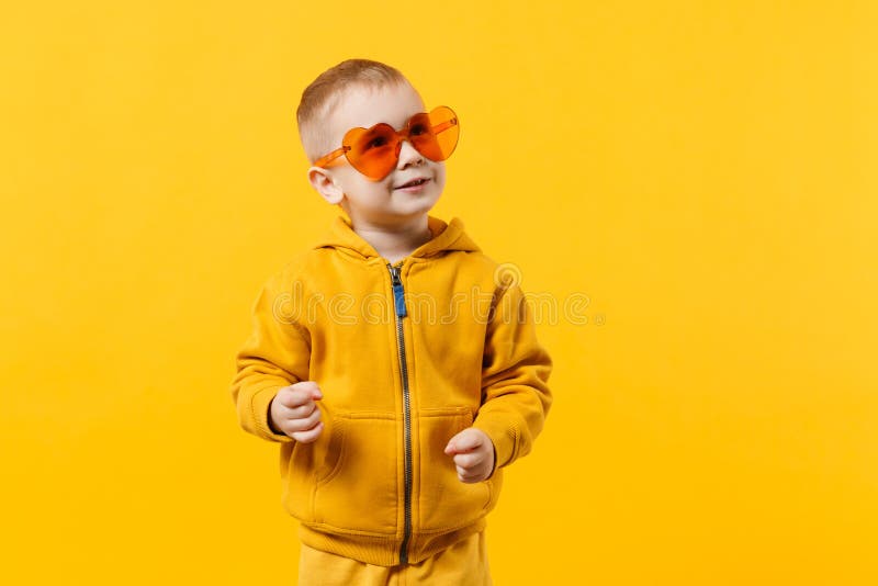 Маленький милый мальчик ребенк 3-4 лет нося желтых одежд изолированных на яркой оранжевой предпосылке стены, студии детей стоковое изображение Маленький милый мальчик ребенк 3-4 лет нося желтых одежд изолированных на яркой оранжевой предпосылке стены, студии детей стоковое изображение