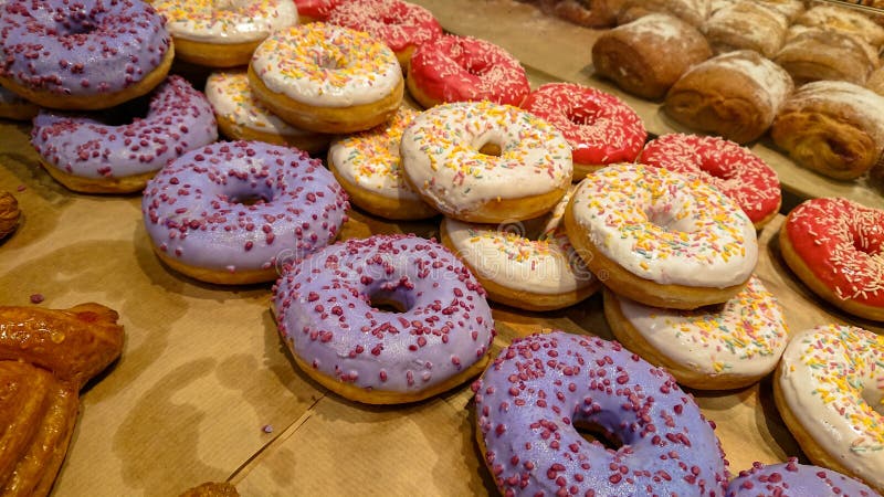 На шкафе в пекарне, много больших великолепных donuts с поливой в красивых цветах стоковые изображения rf На шкафе в пекарне, много больших великолепных donuts с поливой в красивых цветах стоковые изображения rf