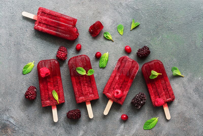 Плоские положенные домодельные popsicles мороженого ежевики поленик украсили ягоды и листья мяты внутри в плите с кубами льда дал стоковая фотография rf Плоские положенные домодельные popsicles мороженого ежевики поленик украсили ягоды и листья мяты внутри в плите с кубами льда дал стоковая фотография rf
