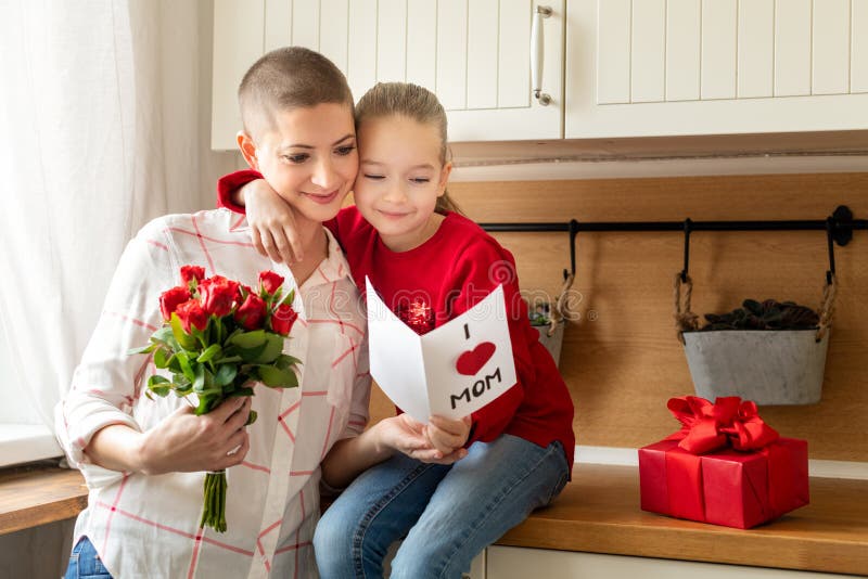 Прелестная маленькая девочка и ее мама, молодой онкологический больной, читая домодельную поздравительную открытку скрепляет болт стоковое фото Прелестная маленькая девочка и ее мама, молодой онкологический больной, читая домодельную поздравительную открытку скрепляет болт стоковое фото