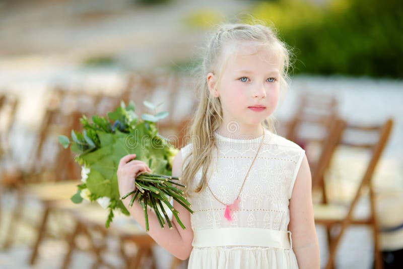 Прелестный маленький bridesmaid держа красивые букеты цветка после outdoors свадьбы cemerony стоковая фотография Прелестный маленький bridesmaid держа красивые букеты цветка после outdoors свадьбы cemerony стоковая фотография