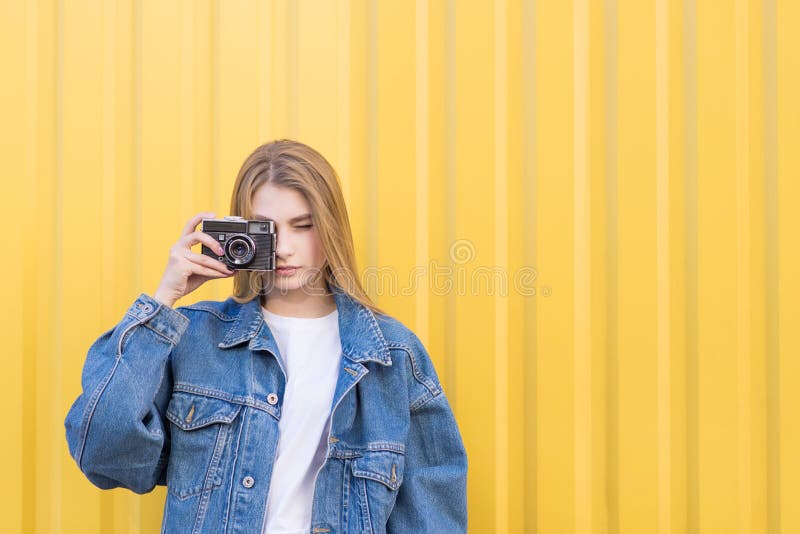 Привлекательная девушка hipist сфотографированная на камере фильма на желтой предпосылке стоковое изображение Привлекательная девушка hipist сфотографированная на камере фильма на желтой предпосылке стоковое изображение