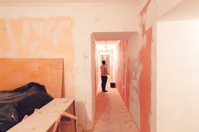 Работник красит потолок роликом краски в коридоре квартира конструкция inder, remodeling, реновация стоковая фотография rf Работник красит потолок роликом краски в коридоре квартира конструкция inder, remodeling, реновация стоковая фотография rf