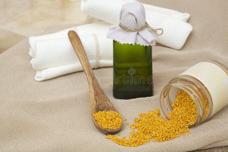 A glass bottle of bee propolis oil. Bee propolis grains in the background. A glass bottle of bee propolis oil. Bee propolis grains in the background.