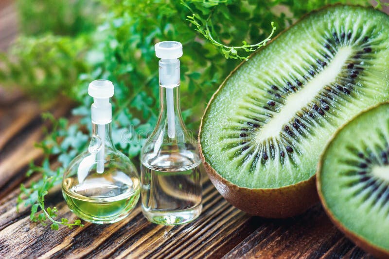 Óleo essencial na garrafa de vidro com fruto de quivi fresco, suculento e tratamento verde da folha-beleza Conceito dos termas Fo foto de stock royalty free Óleo essencial na garrafa de vidro com fruto de quivi fresco, suculento e tratamento verde da folha-beleza Conceito dos termas Fo foto de stock royalty free
