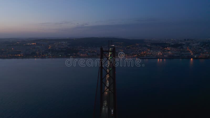 órbita nocturna aérea del puente rojo ponte 25 de abril con tráfico de coches y luces frente a la costa del centro de lisboa almacen de metraje de vídeo